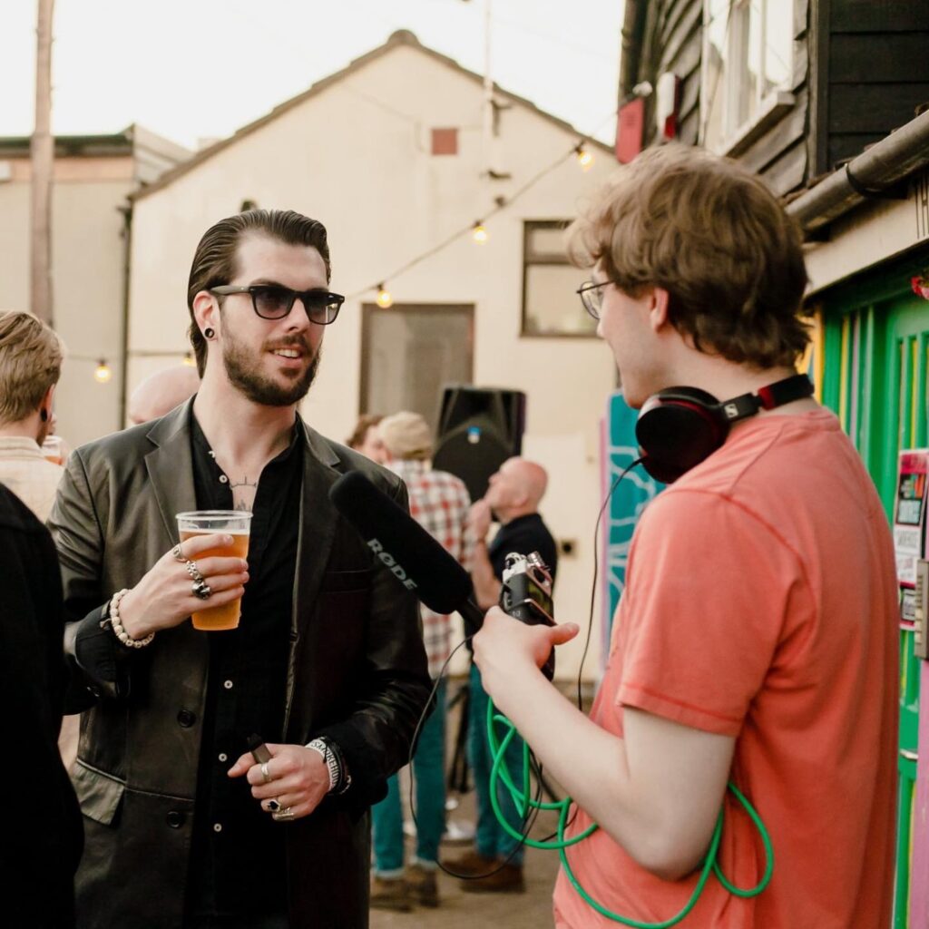 Man being interviewed by Greyhound Creative employee wearing headphones at the Smokehouse in Ipswich.